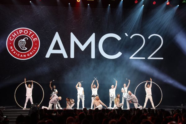 Dancers on stage with Chipotle AMC on screen in background